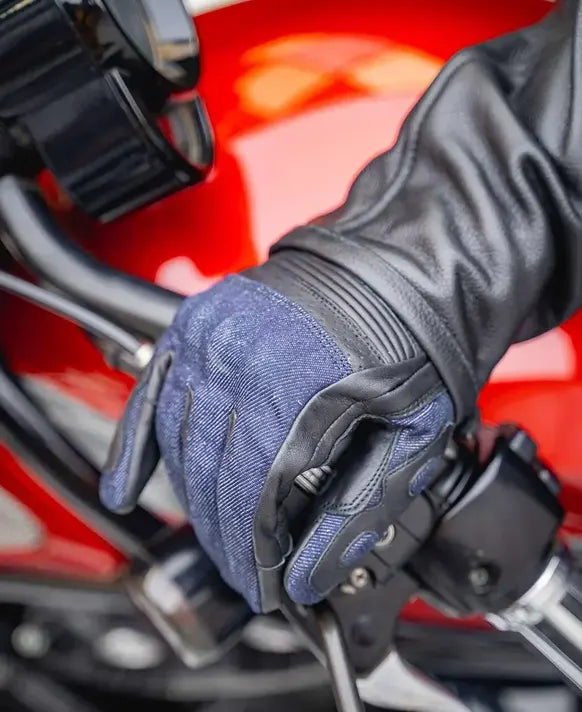 Close-up of a gloved hand on a motorcycle handlebar with a red background