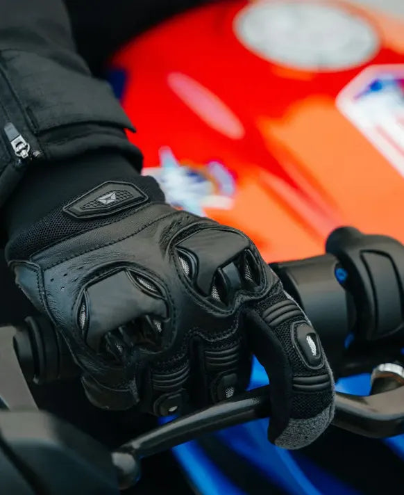 Black motorcycle glove on a gloved hand against a blurred background